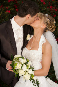 Braut mit Hiochsteckfrisur, sinnlicher Kuss eines Brautpaares
